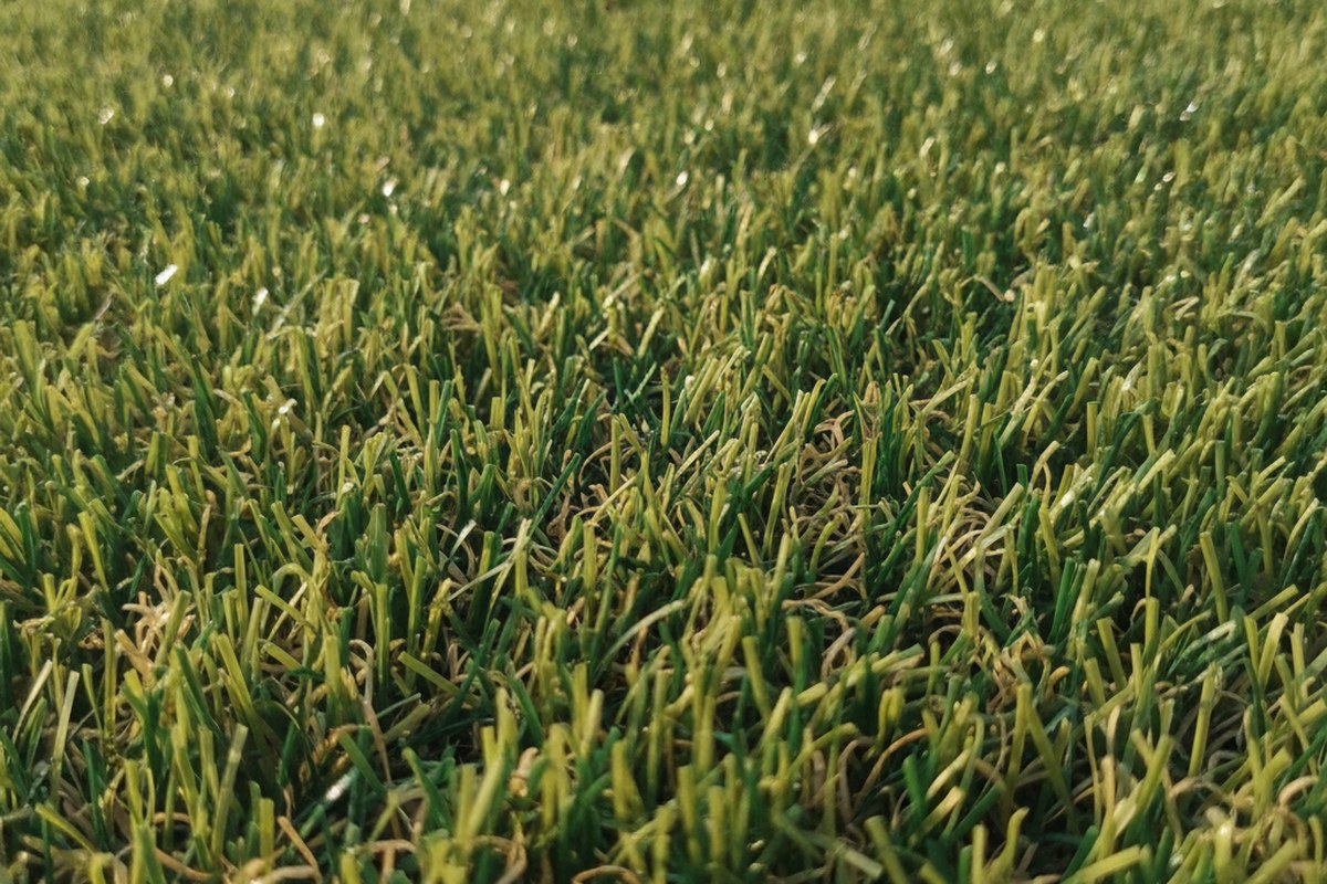 Macro view of 30mm artificial grass pile showing mixed green yarn